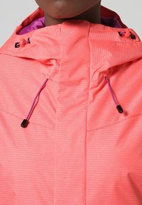 Rosa vattentät jacka med ett texturerat mönster, med en hög krage, justerbara snoddar och svarta detaljer i metall.