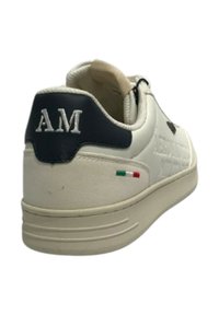 Sneaker bianca in pelle con tallone blu navy, ricamo "AM" e piccolo dettaglio della bandiera italiana sul retro. Presenta una punta arrotondata e suola in gomma.