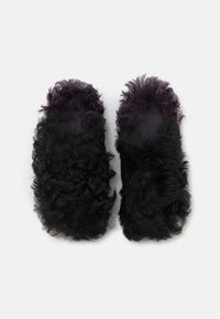 Svarta fluffiga tofflor med lockig textur och lila insida; öppen tå-design, mjukt material och platt sula.