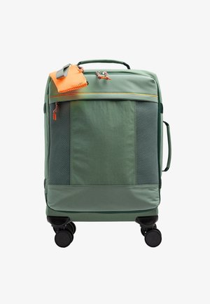 Zielona miękka walizka na czterech kółkach, z przednimi kieszeniami z siatki, pomarańczowymi suwaczkami i pomarańczową siateczkową saszetką przymocowaną do górnej rączki.