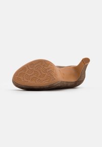 Zapato de ante tipo slip-on en marrón, con una suela de goma flexible con un patrón de hojas en relieve y un talón bajo. La textura suave mejora la comodidad.