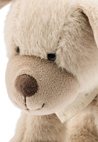 Plush teddy bear with beige fur, a darker brown snout, and stitched eyes. Features a soft texture and a light fabric collar.