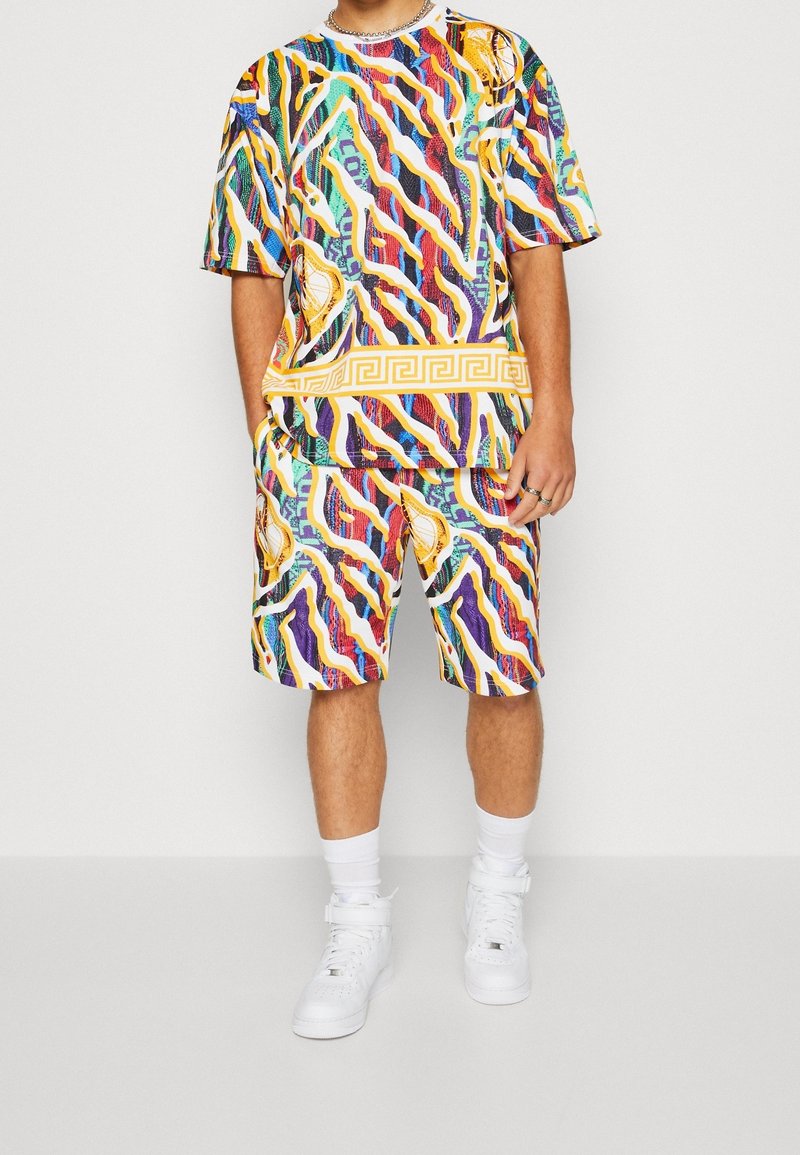 Chemise multicolore et short assorti en tissu léger. Présente des motifs audacieux de lignes ondulées et un motif grec à la taille.