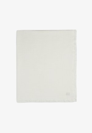 Witte katoenen deken met een gestructureerd, geweven patroon. De randen hebben een franjes trim, wat een zachte, lichte uitstraling biedt.