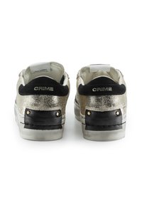 Sneaker metallici dorati con accenti in suede nero sul tallone, dotati di suole bianche, audace branding "CRIME" e dettagli di cucitura decorativa.