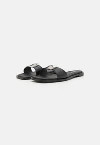 Svarta slidesandaler med en slät ovandel, som har en asymmetrisk silveraccent och en platt gummisula för komfort.
