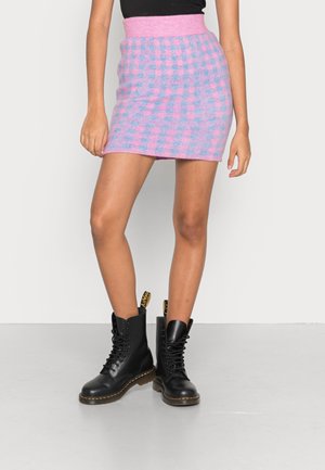 Falda mini de punto en un patrón de cuadros rosa y azul con una cinturilla acanalada, combinada con botas de combate negras con cordones.