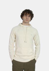 Felpa crema con tasca a canguro, cappuccio con cordino e polsini a costine. Presenta un piccolo logo sul lato sinistro del petto. Tessuto morbido, design casual.