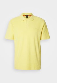 Polo à manches courtes jaune clair avec col, patte à deux boutons et logo "BOSS" en relief subtil sur la poitrine.