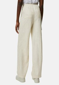 Beiga linnbyxor med vida ben och elastiskt midjeband, som har två bakfickor och en mjuk textur, i kombination med vita sneakers.