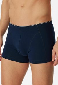 Navy blue cotton boxer shorts featuring a fitted design, elastic waistband with a contrasting trim, and a front pouch. Smooth texture.