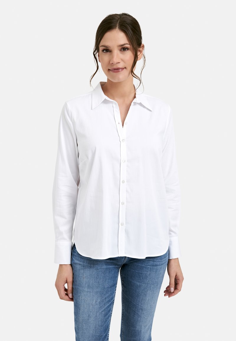 White long-sleeve button-up shirt with a collar, featuring a smooth fabric texture and a curved hem. Paired with blue jeans.