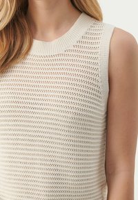 Beżowy, bezrękawnikowy sweter z okrągłym dekoltem ribbed i teksturowanym wzorem z otwartym splotem. Lekki i przewiewny materiał.