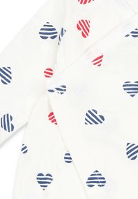 Weißes Kleidungsstück mit rot-blauen gestreiften Herzen in einem wiederholenden Muster. Weicher Stoff mit Druckknopfverschluss an der Seite.