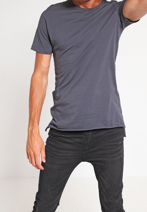 Ciemnoszary T-shirt z krótkim rękawem z miękkiego, elastycznego materiału, z okrągłym dekoltem i luźnym krojem, zestawiony z dopasowanymi czarnymi jeansami.