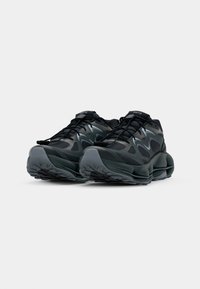 Zwarte en grijze sneakers met een camouflagedessin, bovenkant van mesh, gevoerde kraag en dikke, textuur gegeven zool ontworpen voor comfort en stabiliteit.