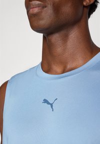 Light blue sleeveless athletic shirt in soft fabric, featuring a dark blue Puma logo on the chest and a round neckline.