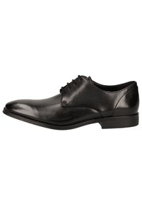 Chaussure habillée pour homme en cuir verni noir, avec un bout pointu, un laçage et un petit talon empilé, présentée de profil sur un fond blanc.