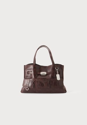 Sac à main en cuir marron foncé avec deux poignées, boucle frontale et une petite étiquette en métal suspendue sur le côté droit.