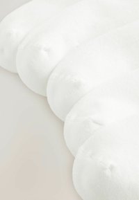 Quatre paires de chaussettes basses blanches unies, disposées côte à côte sur une surface claire, montrant les zones des orteils et du pied.