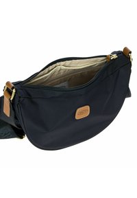 Borsa a tracolla nera in nylon con forma curvata, dettagli in pelle, chiusura con zip e fodera interna beige che presenta più scomparti.