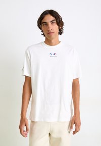 Hvid bomulds t-shirt med korte ærmer, der har BMW Motorsport-logoet i centrum. Enkel design med rund halsudskæring og afslappet pasform.