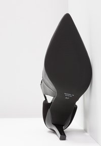 Černá lodička na vysokém podpatku s špičatou špičkou, koženým svrškem a jemnými semišovými detaily, s úzkým, zúženým podpatkem. Velikost 37, vyrobeno ve Španělsku.