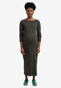 Dunkelgrünes, geripptes Kleid mit langen Ärmeln, schulterfreiem Ausschnitt und mid-calf Länge, kombiniert mit türkisfarbenen Sneakers und einer glatten Textur.