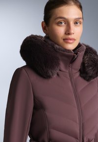 Ljubičasta podstavljena jakna s umjetnim krznom na ovratniku, dijagonalnim šavovima, prednjim patentnim zatvaračem i prilagođenim krojem.