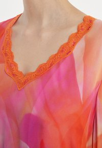 V-Ausschnitt transparente Bluse in einem Verlauf von Pink- und Orangetönen, mit einer detaillierten Orangen-Spitzenkante am Ausschnitt. Glatte Stofftextur.