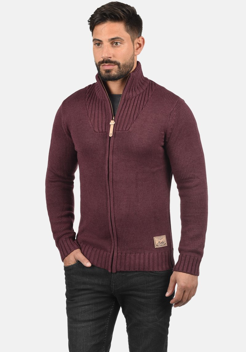 Weinroter Reißverschluss-Pullover mit geripptem Kragen, gestrickter Struktur und einem Leder-Logo-Patch. Verfügt über lange Ärmel und eine lockere Passform.