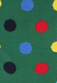 Zielony materiał o teksturowej powierzchni, z różnorodnymi dużymi, okrągłymi kropkami w kolorach niebieskim, czerwonym, żółtym i czarnym.