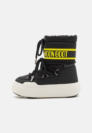 Botte de neige noire et blanche mi-mollet avec de gros lacets noirs, bande de marque jaune "MOON BOOT" et semelle blanche épaisse.