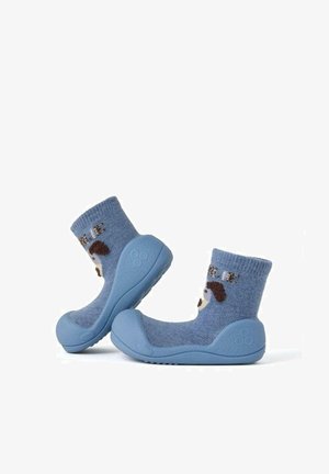 Calcetines de tela azul con un suave tejido en la parte superior que presenta un diseño de perro juguetón. Las suelas de goma proporcionan agarre y durabilidad.