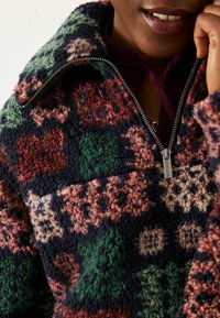 Strukturierter Fleece-Pullover in Navy-, Grün- und Rosamuster. Verfügt über einen hohen Kragen und einen Reißverschluss mit metallischen Beschlägen.