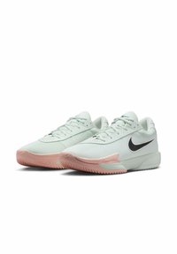 Baskets de sport vert clair avec une tige en mesh texturé, logo swoosh noir, semelle en caoutchouc rose et design à lacets.