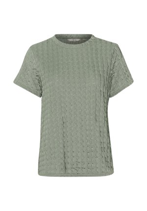 Trumpas žalias marškinėlis su rankovėmis, pagamintas iš tekstūruotos medžiagos su subtiliu raštu. Turi apvalią iškirptę ir laisvą kirpimą.