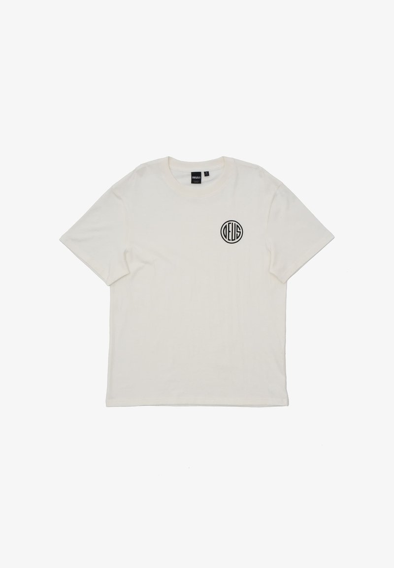 Camiseta de algodón blanca con mangas cortas y cuello redondo, que presenta un logo circular negro en la zona izquierda del pecho. Textura suave.