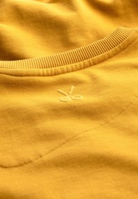 Felpa gialla senape con colletto a costine, caratterizzata da un piccolo logo a forbici ricamato e tessuto a trama fine.