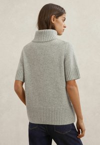 Maglione grigio chiaro in maglia con collo alto a coste e maniche corte, rifinito con orlo a coste. Realizzato in materiale morbido, con una finitura strutturata.