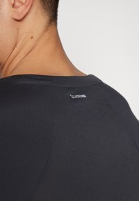 Sort fugttransporterende T-shirt med struktureret finish, der har en flad udskæring og en mærket "CLIMACOOL" label bagpå.