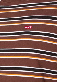 Camiseta a rayas marrón con rayas horizontales en blanco, negro y naranja. Un parche de logo rojo de Levi's está situado en el pecho.