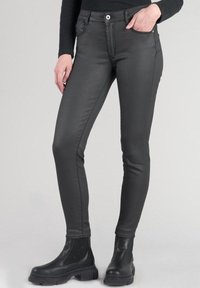 Jeans neri slim-fit realizzati in un materiale morbido, con tasche anteriori, chiusura con zip e dettagli di cucitura a contrasto. Abbinati a stivali neri.