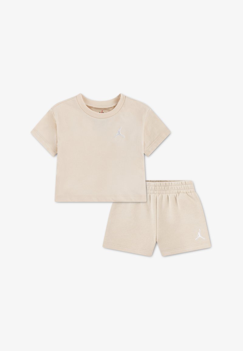 Ensemble t-shirt et short en coton beige. Le t-shirt présente un col rond et des manches courtes avec un logo blanc. Taille élastique sur le short.