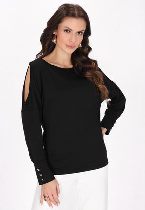 Maglietta nera a maniche lunghe con design a spalla scoperta, caratterizzata da dettagli con bottoni sui polsini e una texture morbida e liscia. Vestibilità casual, scollatura rotonda.