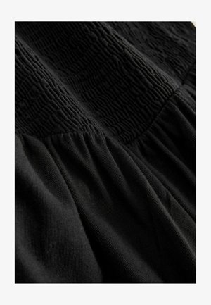 Must kleit, millel on tekstuuriga ülakeha koos kogutud vöökohaga ja sile, voolav seelik. Valmistatud pehmest, kergest kangast.