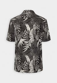 Lyhytnuppuinen, kauluksellinen paita mustana valkoisella trooppisen lehden kuviolla. Kevyt kangas, rento istuvuus, takana yoke-sauma.