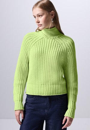 Maglione lavorato a maglia verde brillante con colletto alto, texture a coste e maniche lunghe. Presenta un taglio corto e dettagli in lavorazione a treccia.
