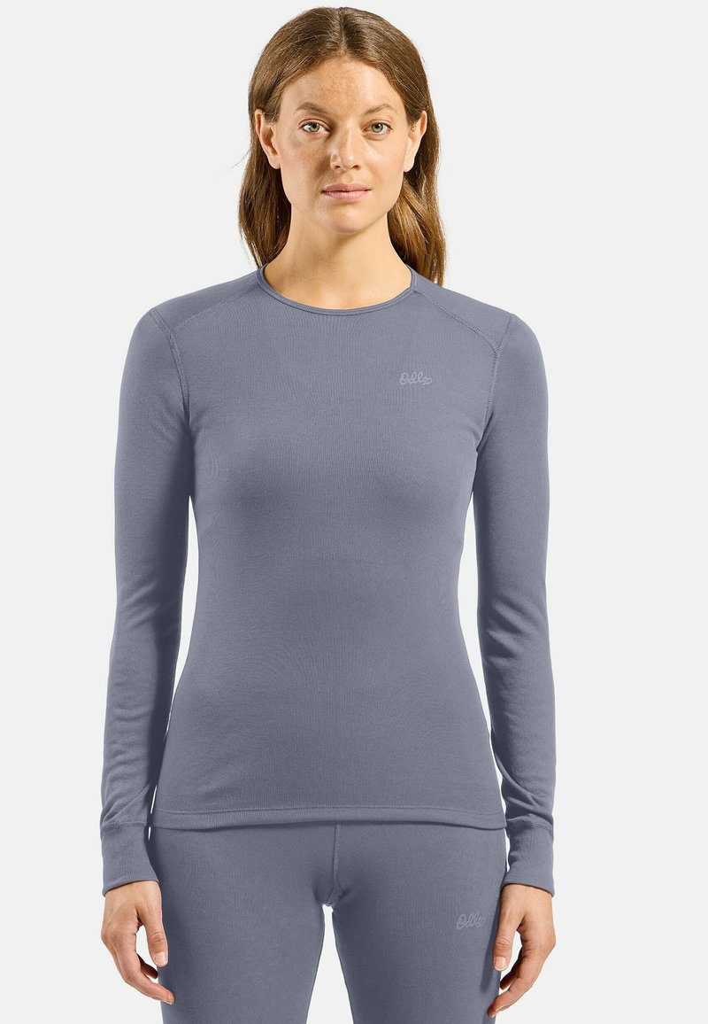 Long-sleeve top in light gray, made from ribbed fabric. Features rounded neckline and subtle brand logo on the chest, fitted design.