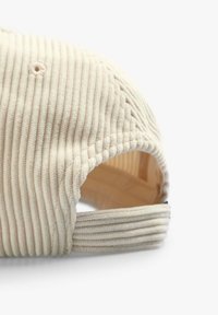 Beige corduroy kasket med ribbet tekstur, buet skygge, justerbar rem bagpå og et ventilationshul på toppen.